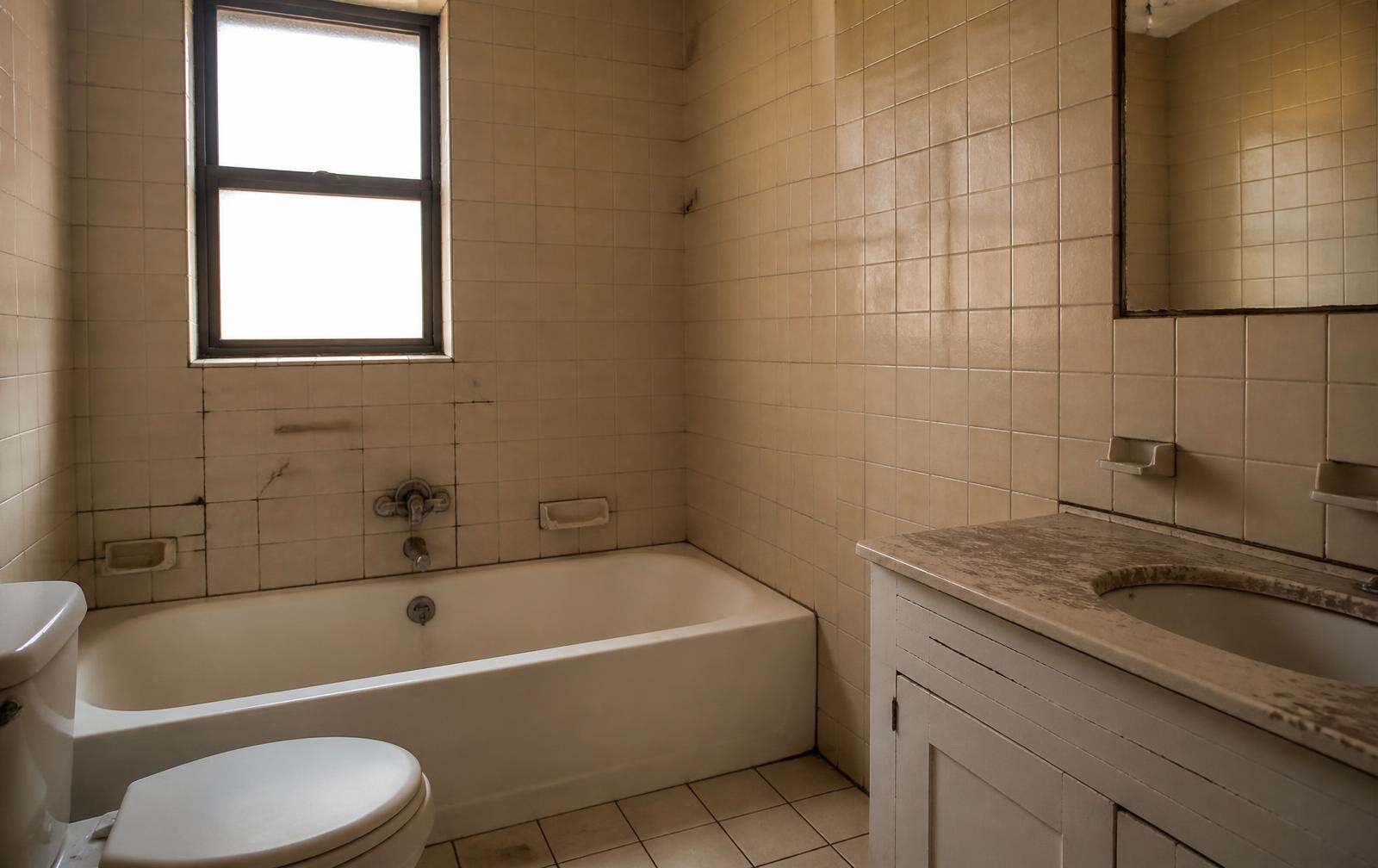 Badkamer voor de renovatie met verouderde tegels